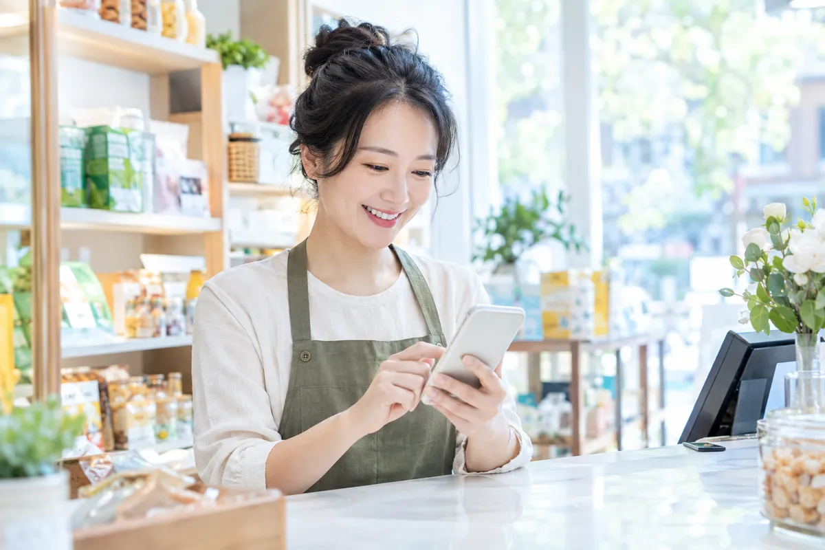 门店老板在柜台前用手机回复用户私信